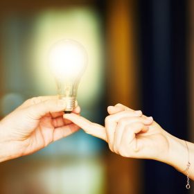 two hands holding a light bulb